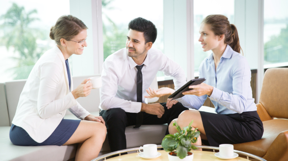Three people having a discussion in an office.