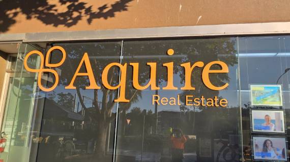 Vinyl lettering of Acquire Real Estate displayed on the company’s entrance glass.