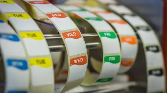 Color-coded weekday stickers arranged on label rolls.
